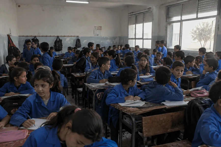 قسم مدرسي مكتظ بتلاميذ يرتدون مآزر زرقاء
